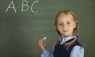 黒板にアルファベットを書く外国の少女